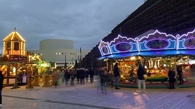 Kö-Bogen-Markt mit Kinderkarussell und Schauspielhaus im Hintergrund.