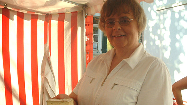 Frau hält Käse in die Kamera