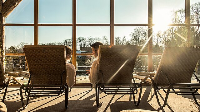Zwei Menschen liegen auf Liegen mit Blick nach draußen