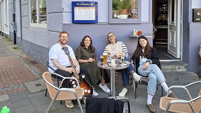 Menschen sitzen vor einer Kneipe