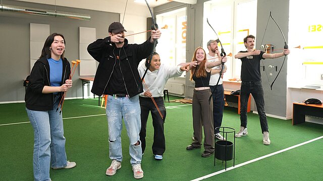 Menschen stehen nebeneinander mit Schießbögen