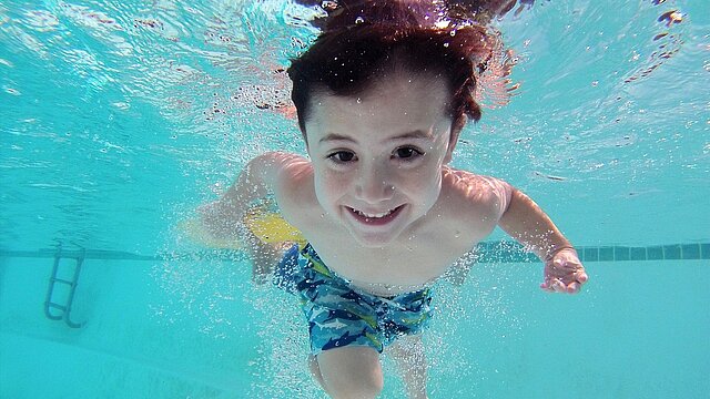 Kind taucht im Schwimmbecken